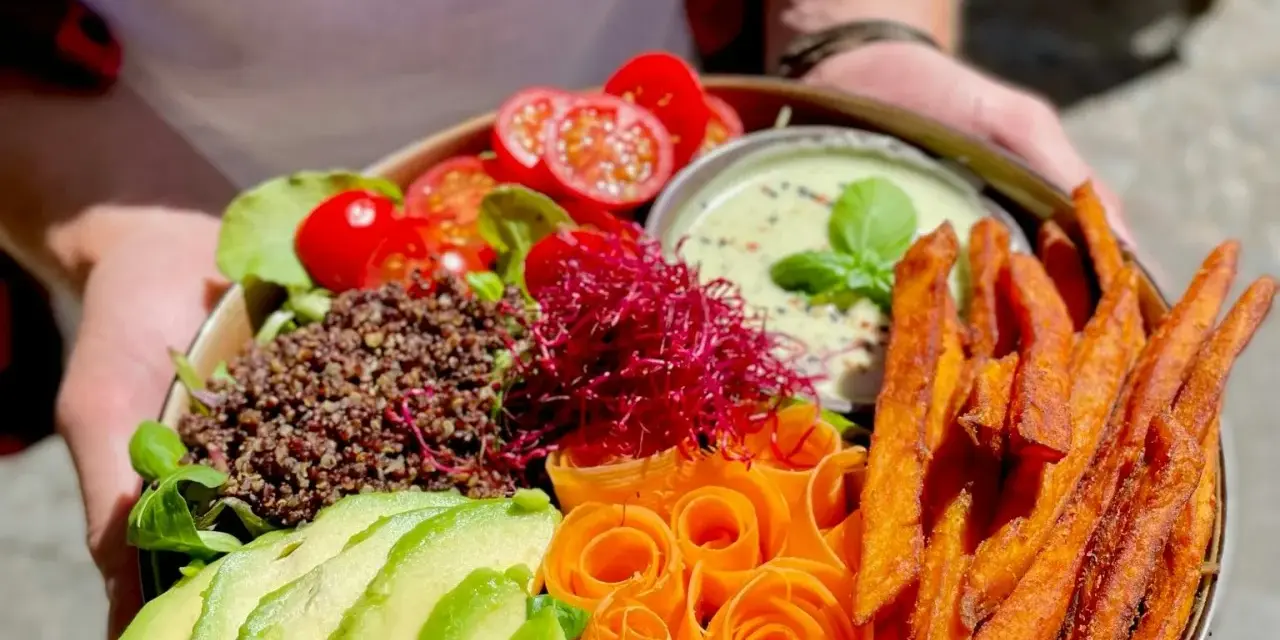 Ein bunter Buddha Bowl mit Avocado, Quinoa, Süßkartoffel-Pommes und Karottenrosen. Ein froindlichst Berlin-Genuss!