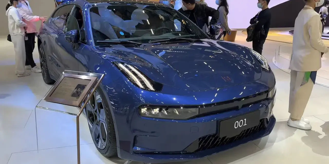 Niebieski Zeekr 001 na wystawie, obok ludzie oglądają auto. Sprawdź zeekr 001 cena i specyfikację.