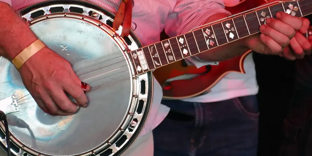Ein Mann spielt ein Banjo, ein Saiteninstrument mit einem runden Korpus und einem langen Hals.