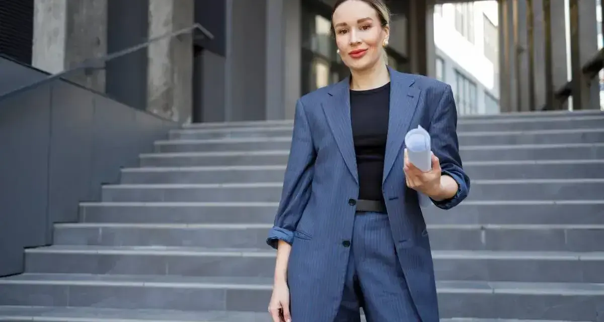 Elegancka kobieta w granatowym garniturze, trzymająca dokumenty, pokazuje, jak ubrać się do sądu.
