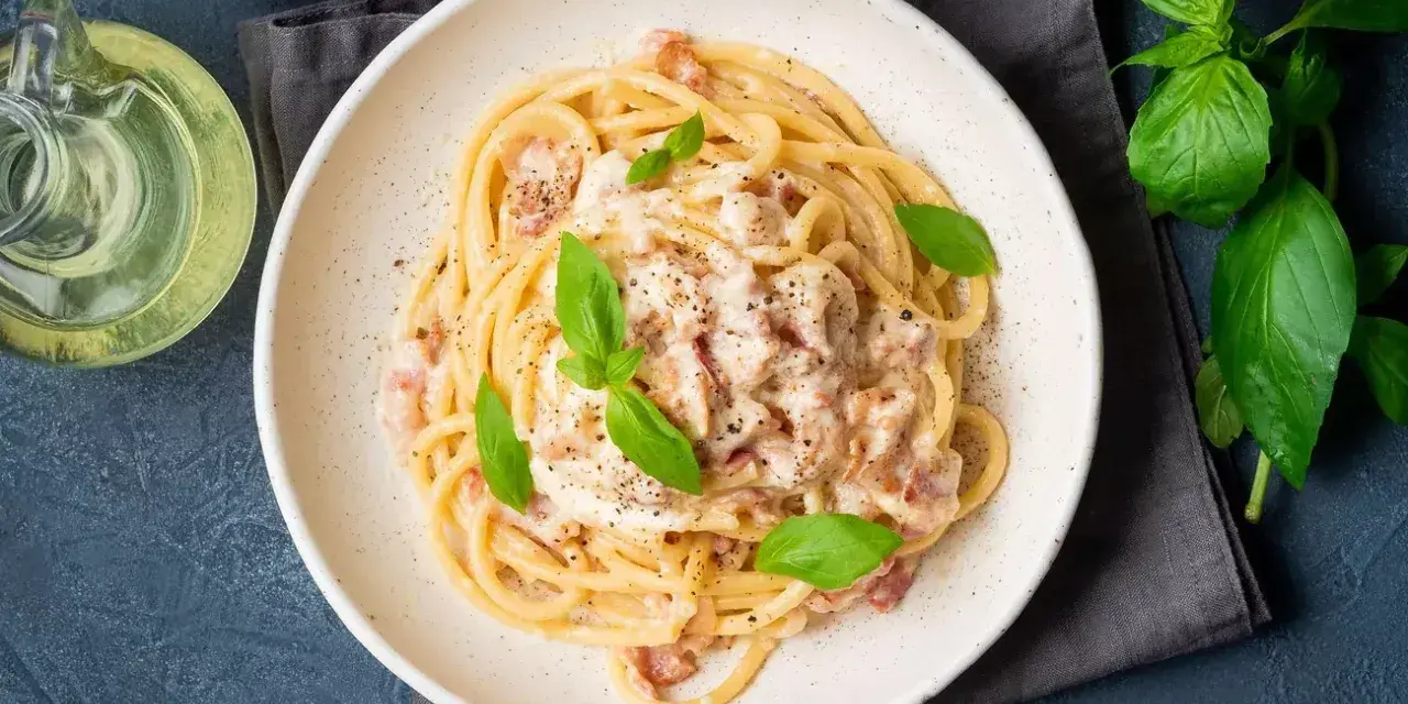 Pyszna carbonara na talerzu, idealna inspiracja, jak zrobić carbonare. Podana z bazylią i pieprzem.