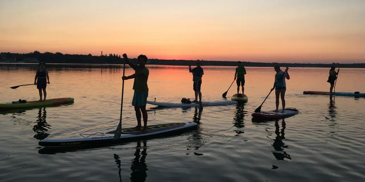 Sonnenuntergang über Berlin: Eine Gruppe genießt Wassersport auf Stand-Up-Paddle-Boards.