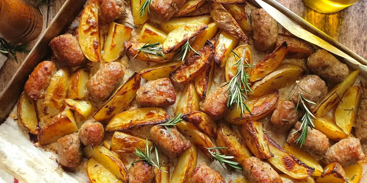 Salsiccia e patate al forno, dorate e profumate al rosmarino, pronte per essere gustate.