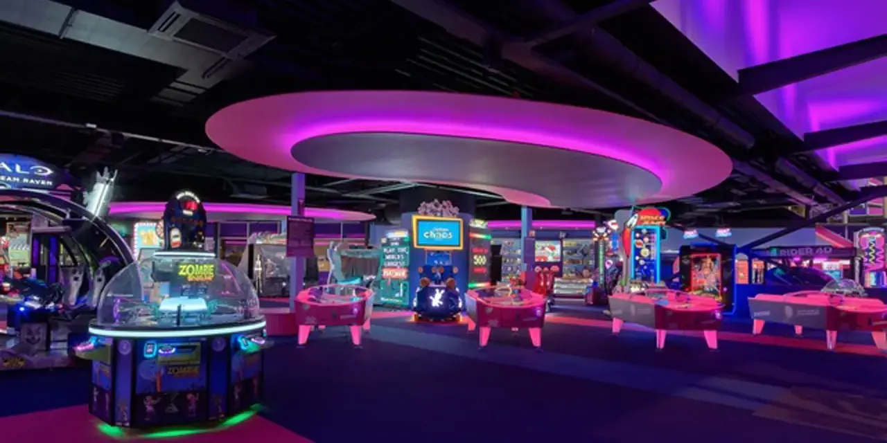Bunte Spielautomaten und Air-Hockey-Tische in einem beleuchteten Gamestate Potsdamer Platz.