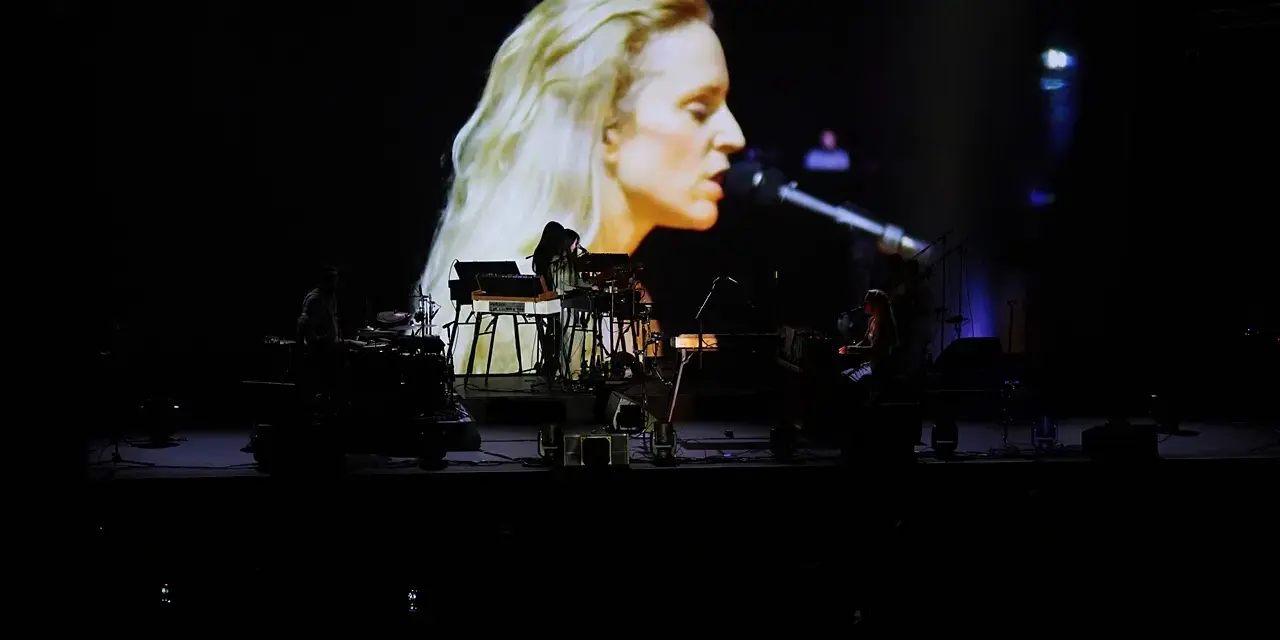 Agnes Obel na ekranie i zespół na scenie podczas koncertu.