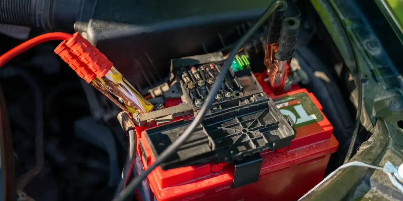 Jump starter cables connected to a car battery. This shows how a jump starter can charge a battery to get your car running again.