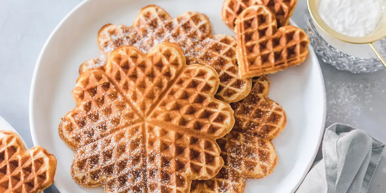 Herzförmige Waffeln mit Puderzucker bestäubt, ein Genuss für Kinder.
