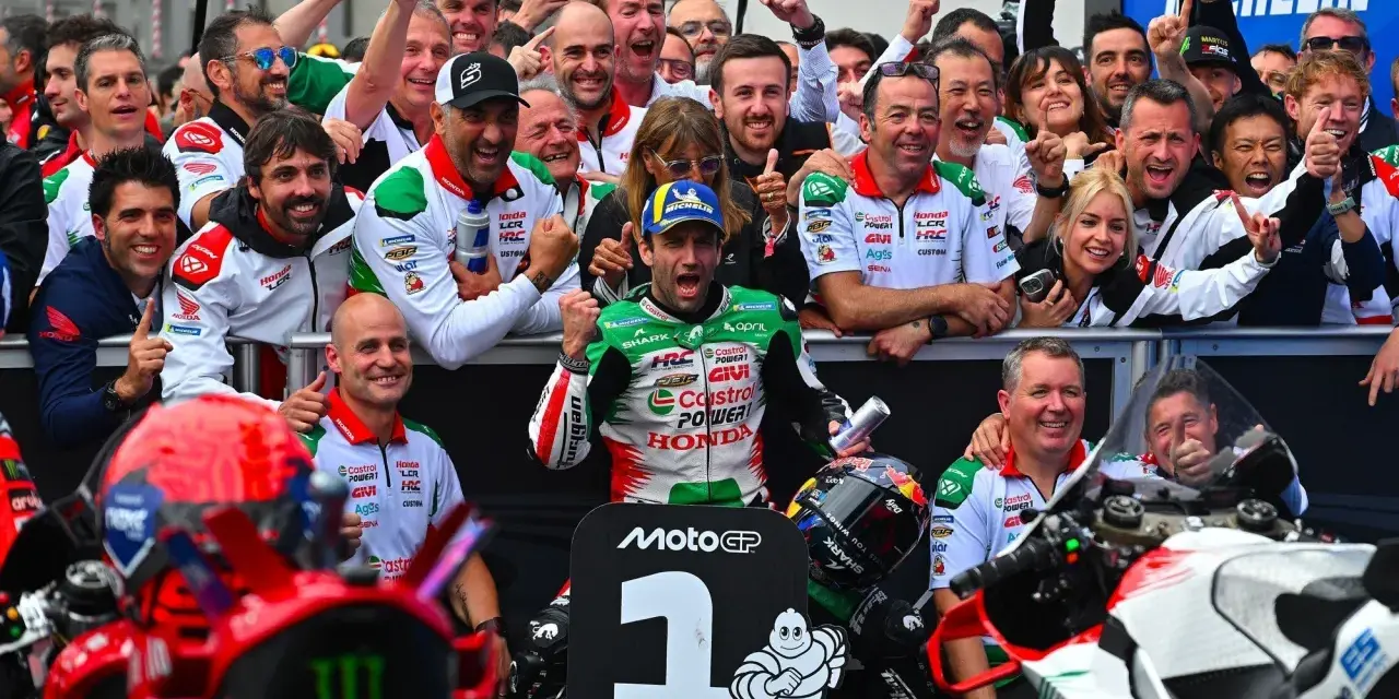 El equipo celebra un podio en el calendario MotoGP. El piloto número 1, rodeado de su equipo, muestra su alegría.