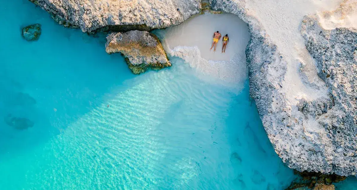 Para na plaży na wyspie Aruba, otoczeni turkusową wodą i skalistymi klifami. Idealne miejsce na relaks.