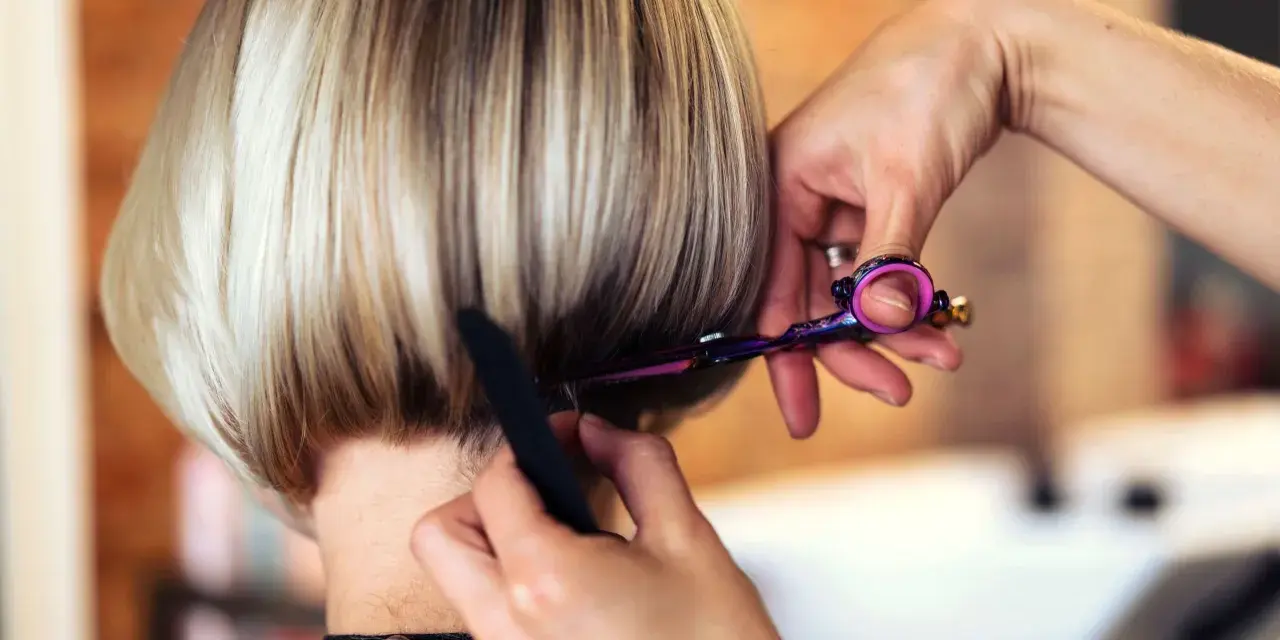 Fryzjerka modeluje cieniowany bob do ramion, używając nożyczek i grzebienia.