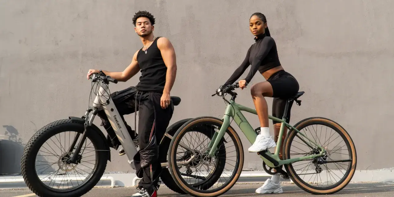 A man and woman pose with their electric hybrid bikes, showcasing a blend of urban style and off-road capability.