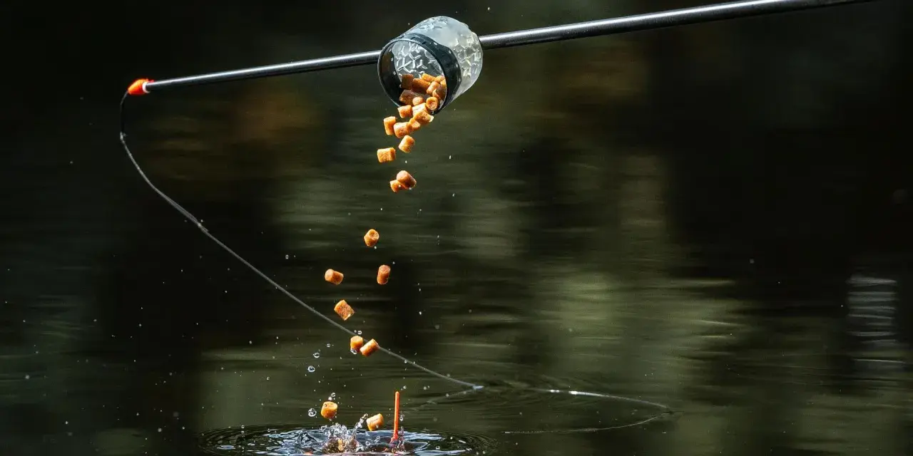 Karmnik method feeder wysypuje zanętę do wody, tworząc chmurę przynęty dla ryb.