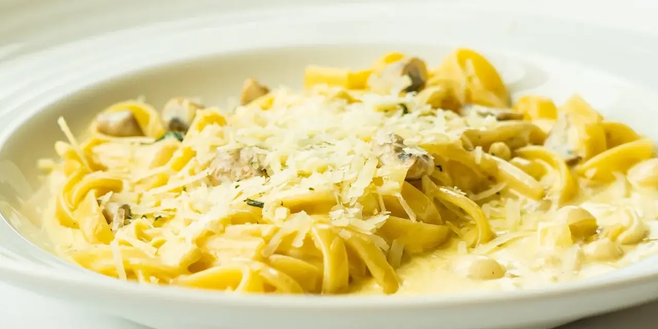 Pyszny makaron z grzybami w kremowym sosie, posypany parmezanem. Idealny przepis na obiad.