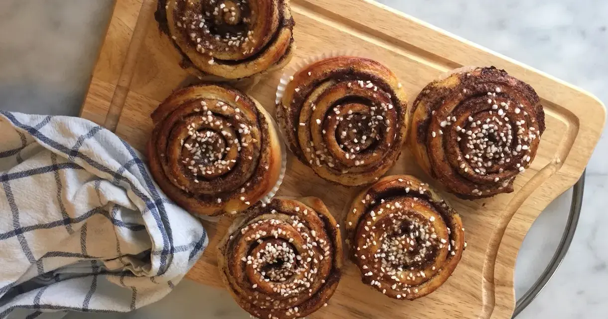 Sju gyllene kanelbullar med pärlsocker, redo att avnjutas. En härlig påminnelse om hur bakar man.