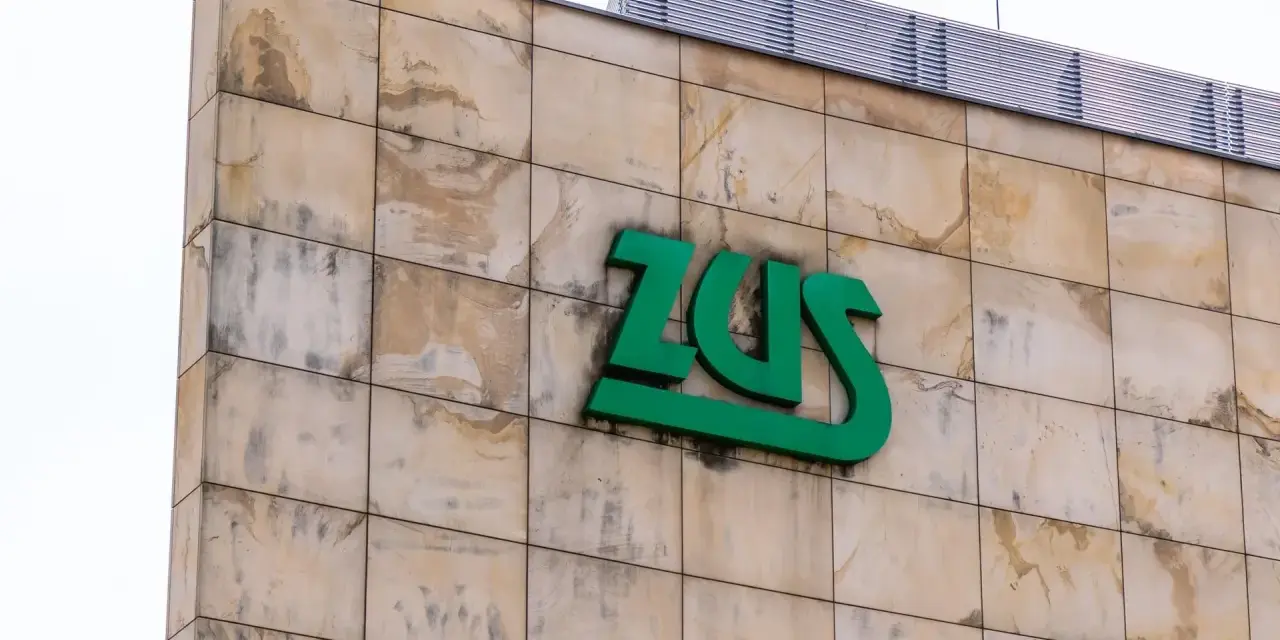 Zielone logo ZUS na beżowej, kamiennej elewacji. Czy chorobowe wlicza się do lat pracy? Zapytaj w ZUS.