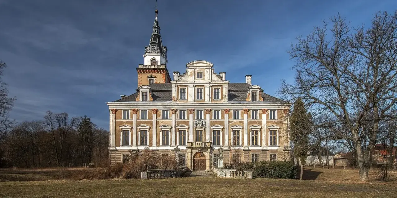 Imponujący zamek w Roztocze, z charakterystyczną wieżą i bogato zdobioną fasadą, otoczony parkiem.