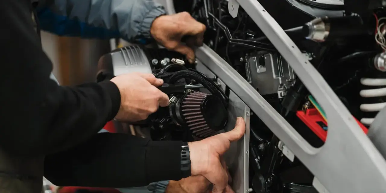 Mechanicy montują nowy filtr powietrza w motocyklu. Zepsuty filtr powietrza objawy to m.in. spadek mocy.