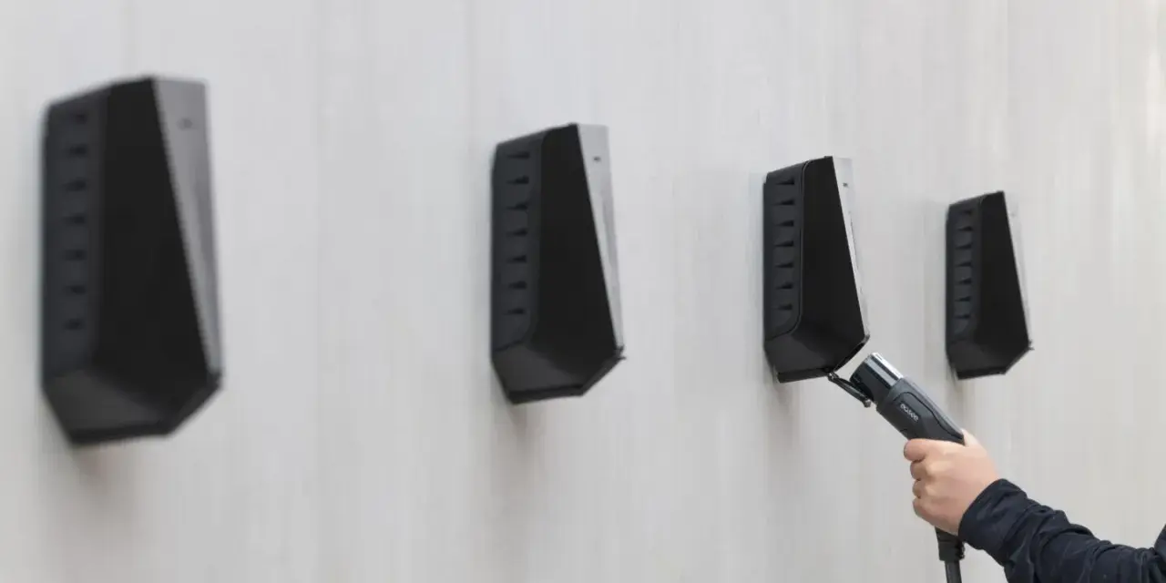 En hand håller en laddkabel mot en Easee laddbox. Ett potentiellt Easee laddbox problem kan vara att kabeln inte kopplas in korrekt.
