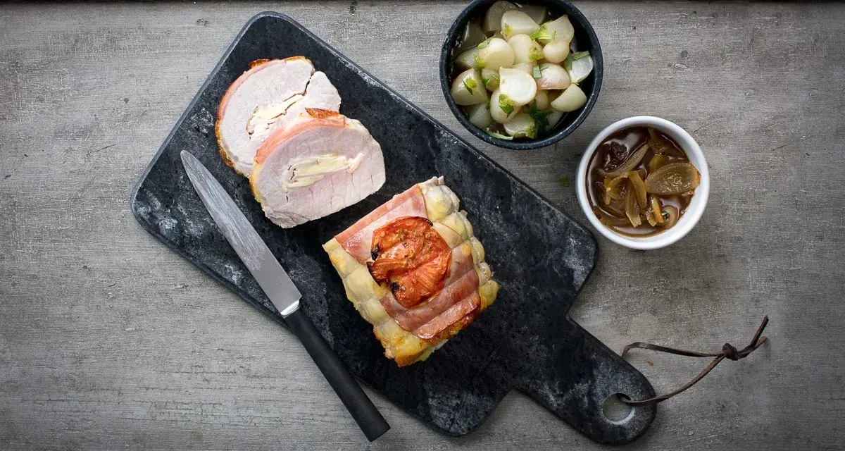 Un délicieux roti de porc Orloff, tranché et garni, accompagné de légumes et d'une sauce onctueuse.