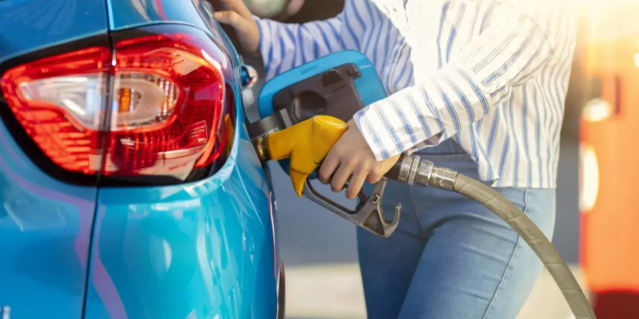 Persona fa rifornimento alla sua auto blu, pensando a come pneumatici con bassa resistenza al rotolamento migliorano l'efficienza.
