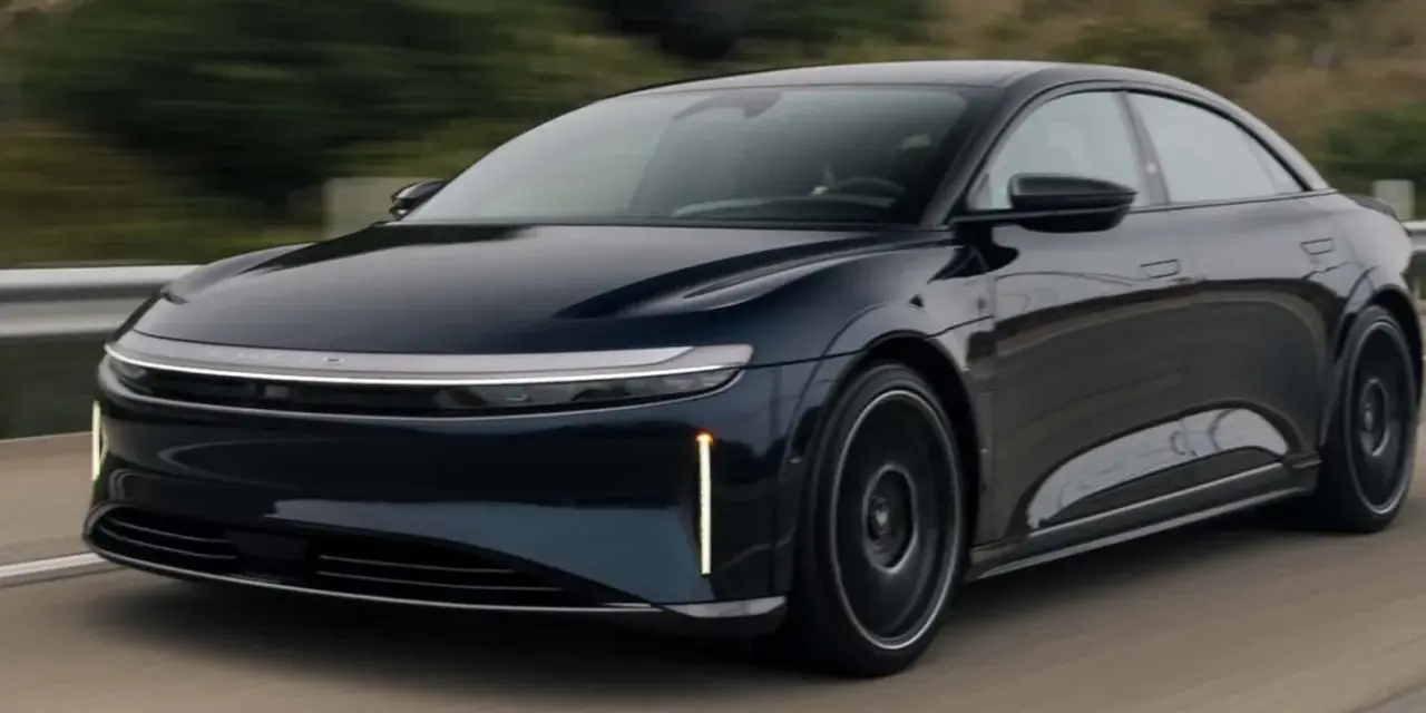 Ciemnoniebieski Lucid Air Sapphire pędzi po drodze, jego aerodynamiczna sylwetka i futurystyczne światła przyciągają wzrok.