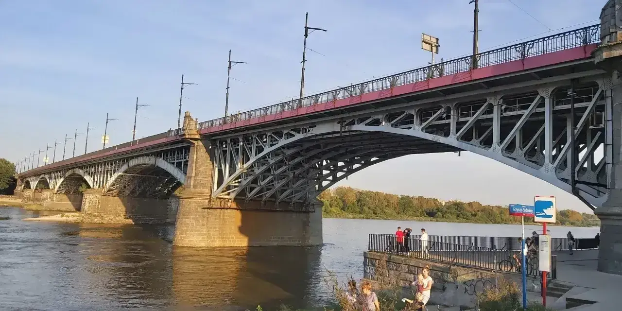 Most Poniatowskiego nad Wisłą, z ludźmi spacerującymi po bulwarach i podziwiającymi architekturę.
