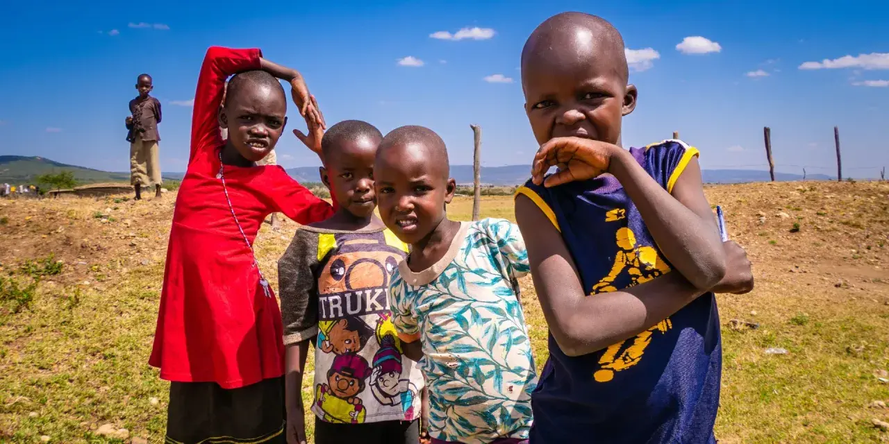 Dzieci z plemienia Masajów, żyjących w Kenii i Tanzanii, pozują do zdjęcia na tle sawanny.