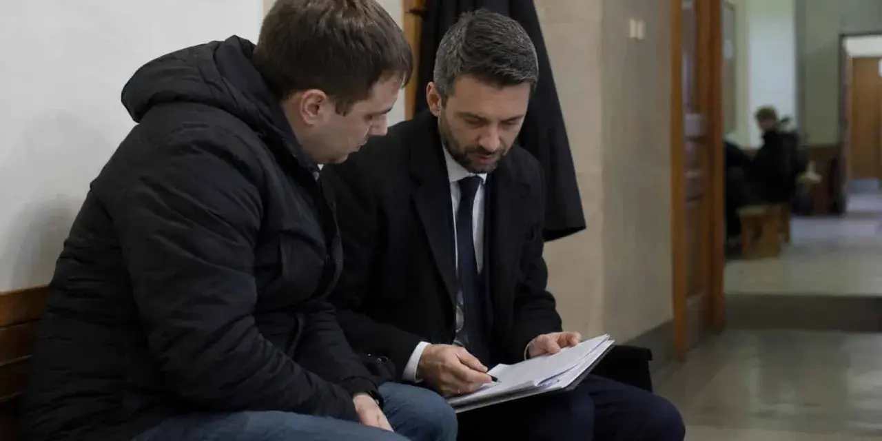 Prawnik omawia z klientem dokumenty dotyczące dobrowolnego poddania się karze a warunkowego umorzenia postępowania.