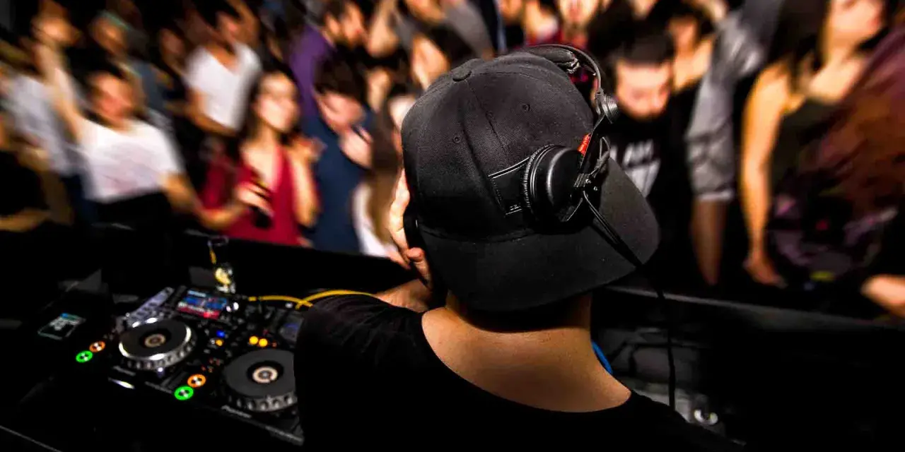 DJ aux platines, casque sur les oreilles, gérant le niveau sonore pour une foule en délire.