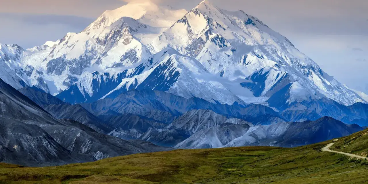 Majestatyczny, ośnieżony szczyt Denali, jednego z najwyższych szczytów kontynentów, góruje nad surowym krajobrazem.