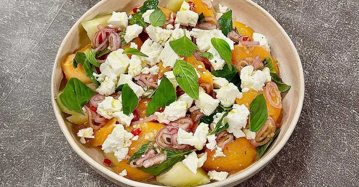 En uppfriskande melon och fetaostsallad med basilika och rödlök. Perfekt sommarbuffé.