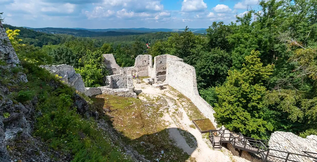 Ruiny zamku Pilcza w Smoleniu, otoczone bujną zielenią, z widokiem na malownicze wzgórza.