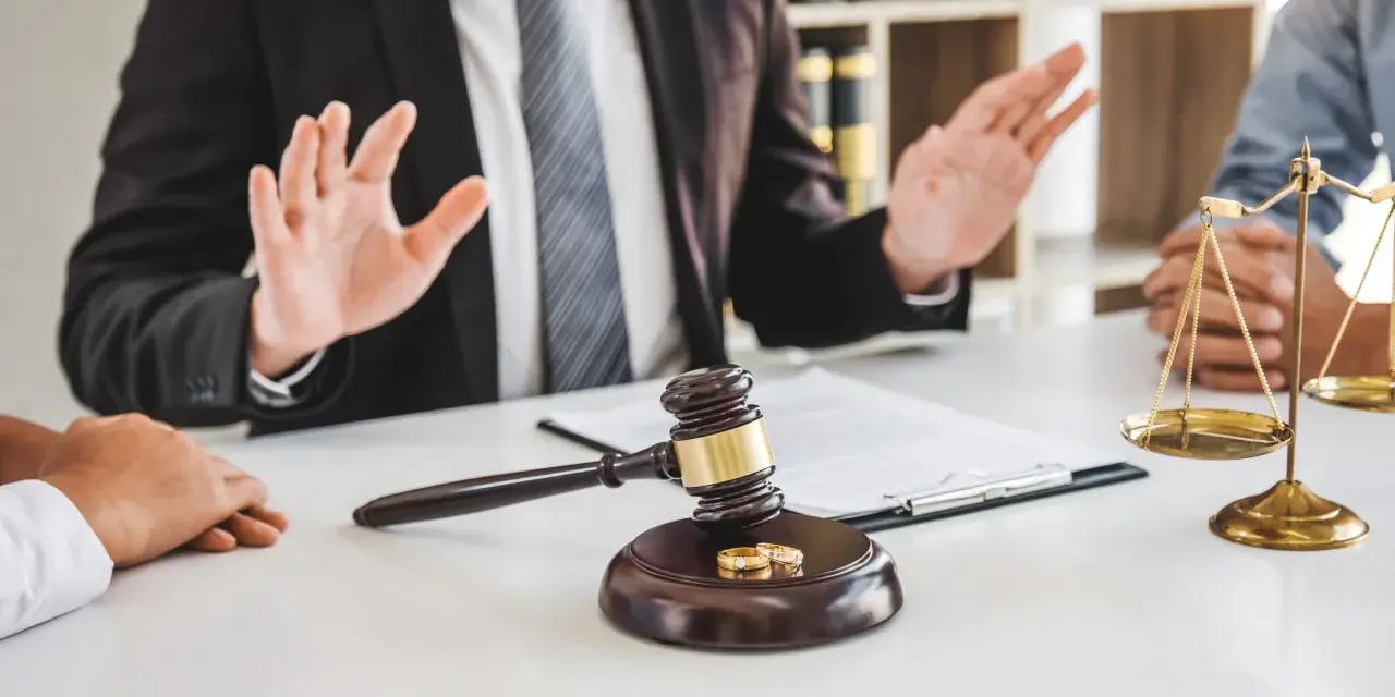 Un avocat explique les démarches pour un papier divorce mairie. Marteau de juge, alliances et balance de la justice sur la table.