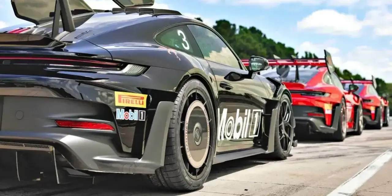 Czarny Porsche GT3 RS z numerem 3 i logo Manthey na skrzydle, gotowy do wyścigu obok czerwonych samochodów.