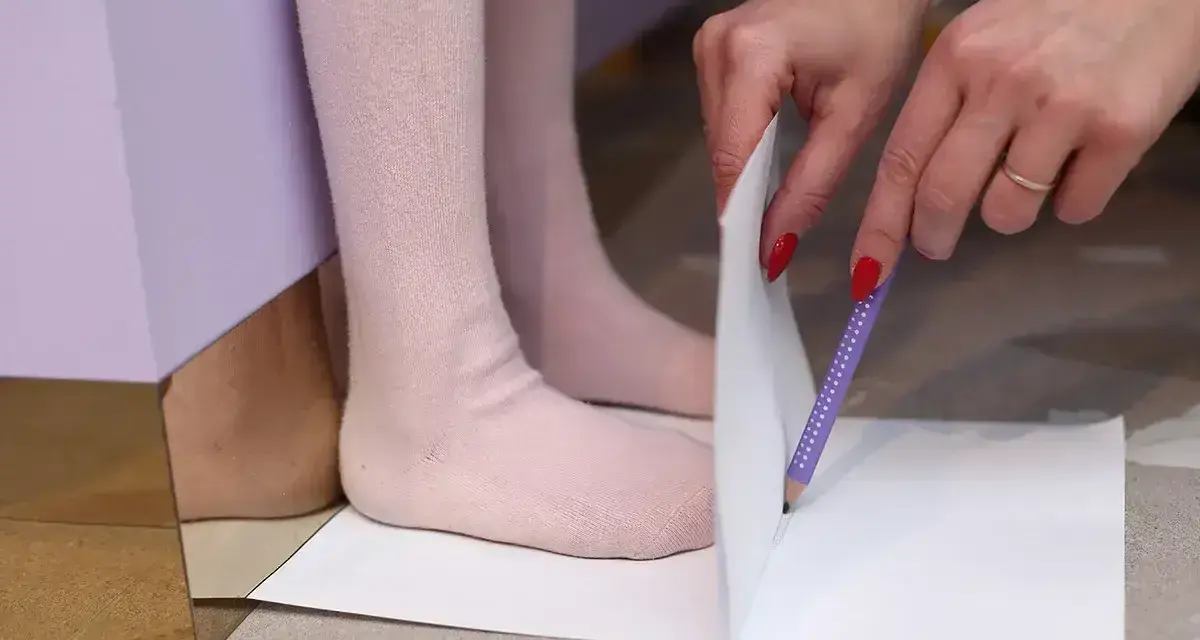 Dziecko mierzy stopę, by dowiedzieć się, jaki to rozmiar buta. 15 cm to idealny pomiar dla małych stópek.
