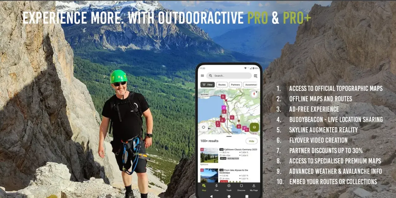 Escursionista sorridente in montagna, con smartphone che mostra l'app outdooractive gratis con mappe e percorsi.