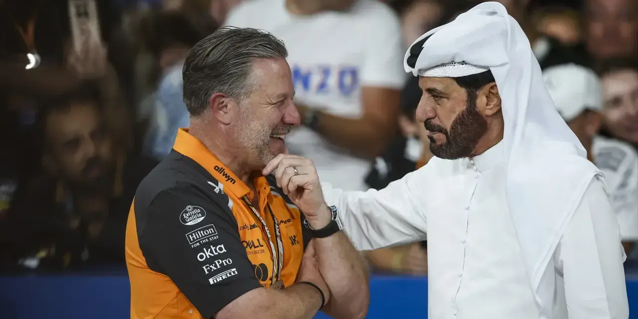 Mohammed Ben Sulayem, con túnica blanca, conversa animadamente con un hombre con polo naranja de McLaren.