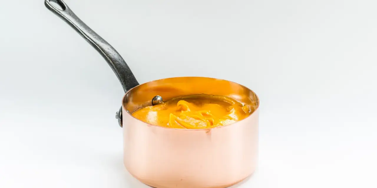 Cazo de cobre con puré de boniato cremoso y naranja, listo para servir.