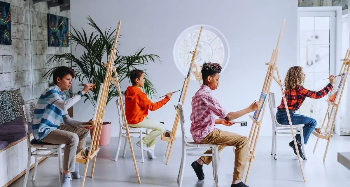 Des enfants concentrés sur leur peinture sur toile facile, créant des œuvres colorées dans un atelier lumineux.