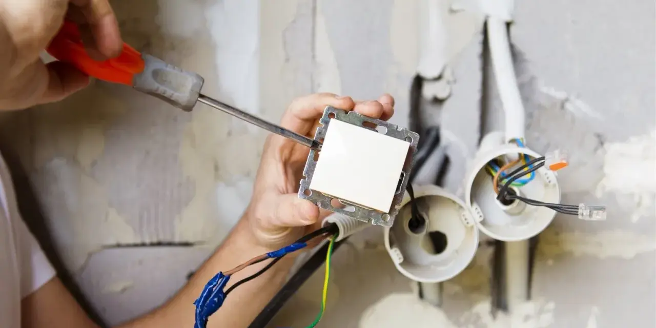 Elektryk montuje włącznik światła. Zastanawiasz się, ile kosztuje prąd budowlany?