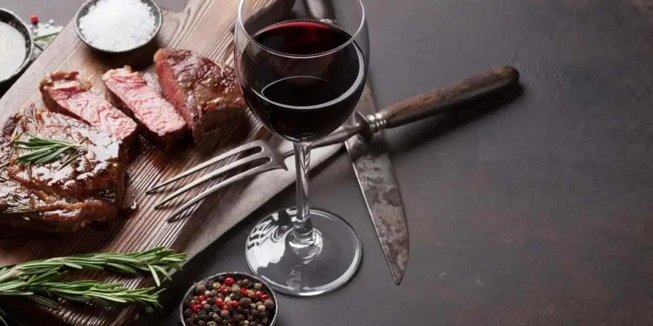 En saftig entrecote, perfekt tillagad, med ett glas rött vin. Kryddor och rosmarin fulländar upplevelsen.