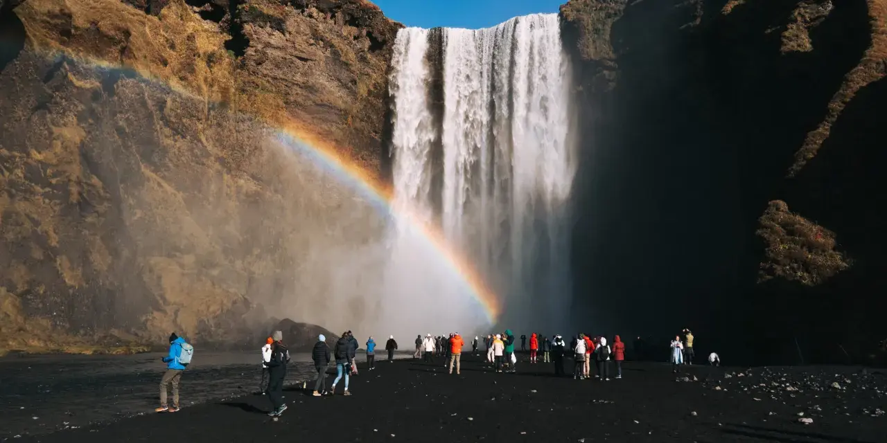 Turyści pod wodospadem Skógafoss na Islandii. Czy do Islandii trzeba mieć paszport? Tak, dla obywateli spoza strefy Schengen.