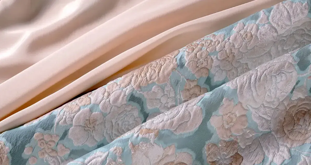 Tissu texturé bleu ciel avec des motifs floraux et un tissu satiné pêche. Parfait pour une robe d'été élégante.