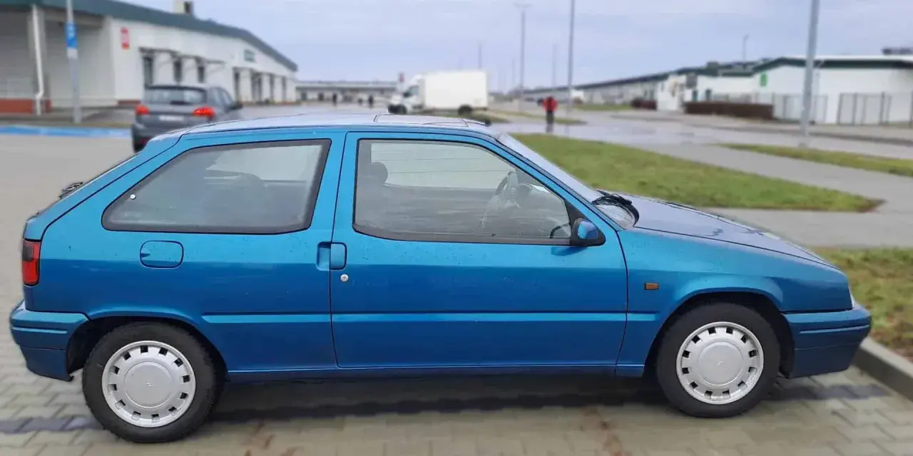 Błękitny Citroen ZX stoi na parkingu.