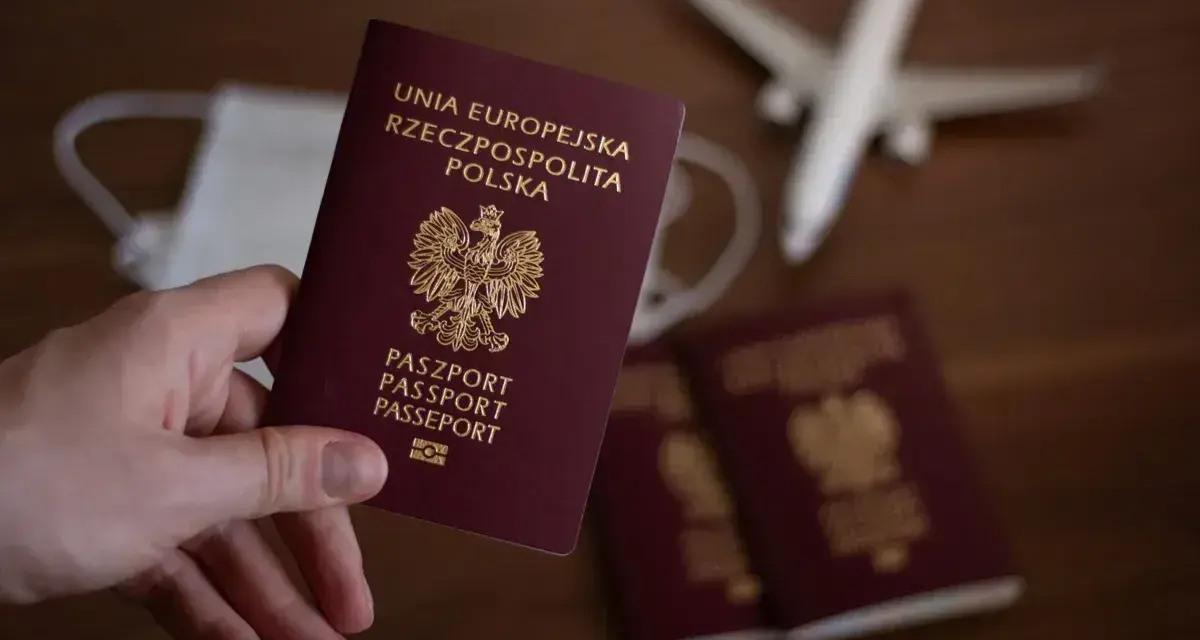 Dłoń trzyma polski paszport. Obok leżą kolejne paszporty, maseczka i samolot. Zastanawiasz się, ile się czeka na paszport?