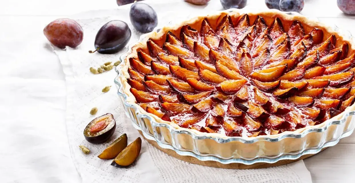 Une délicieuse tarte aux prunes, garnie de fruits frais et dorés, prête à être dégustée.