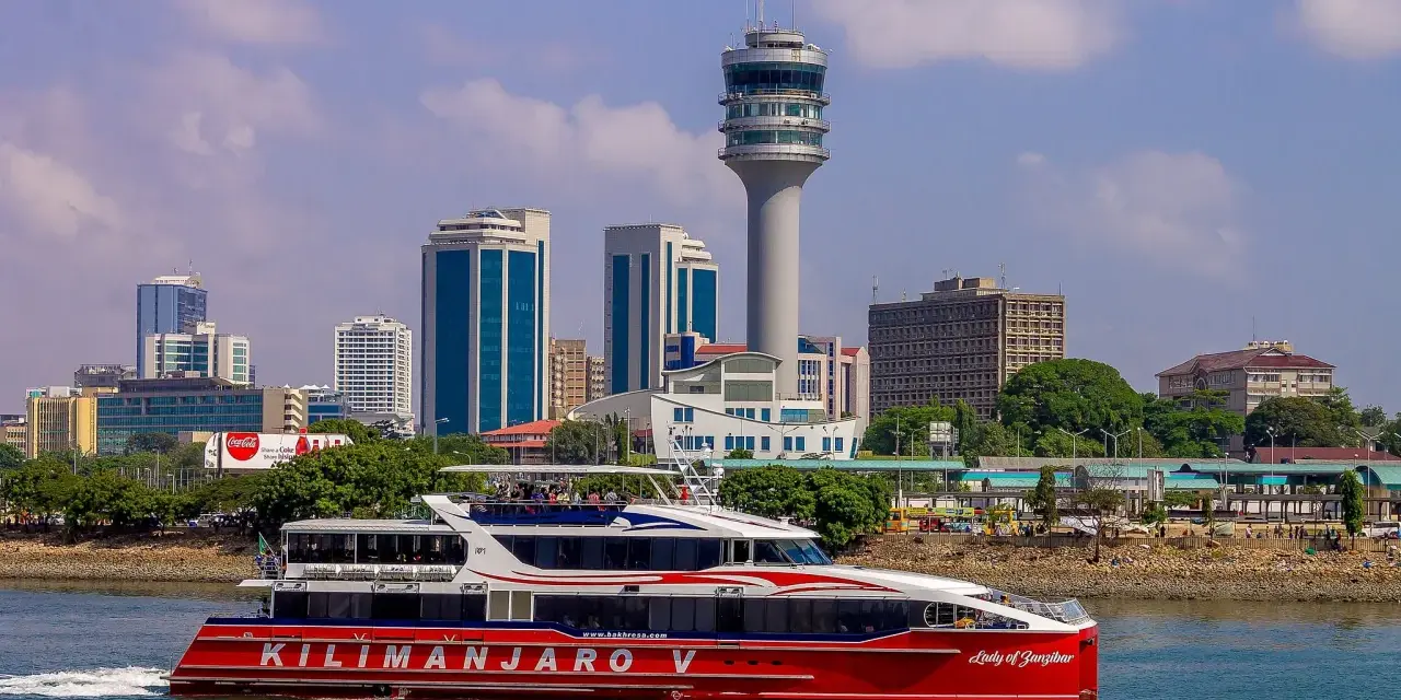 Prom na Zanzibar, "Kilimanjaro V", płynie przy nowoczesnej panoramie Dar es Salaam Tanzania, z charakterystyczną wieżą kontroli lotów.