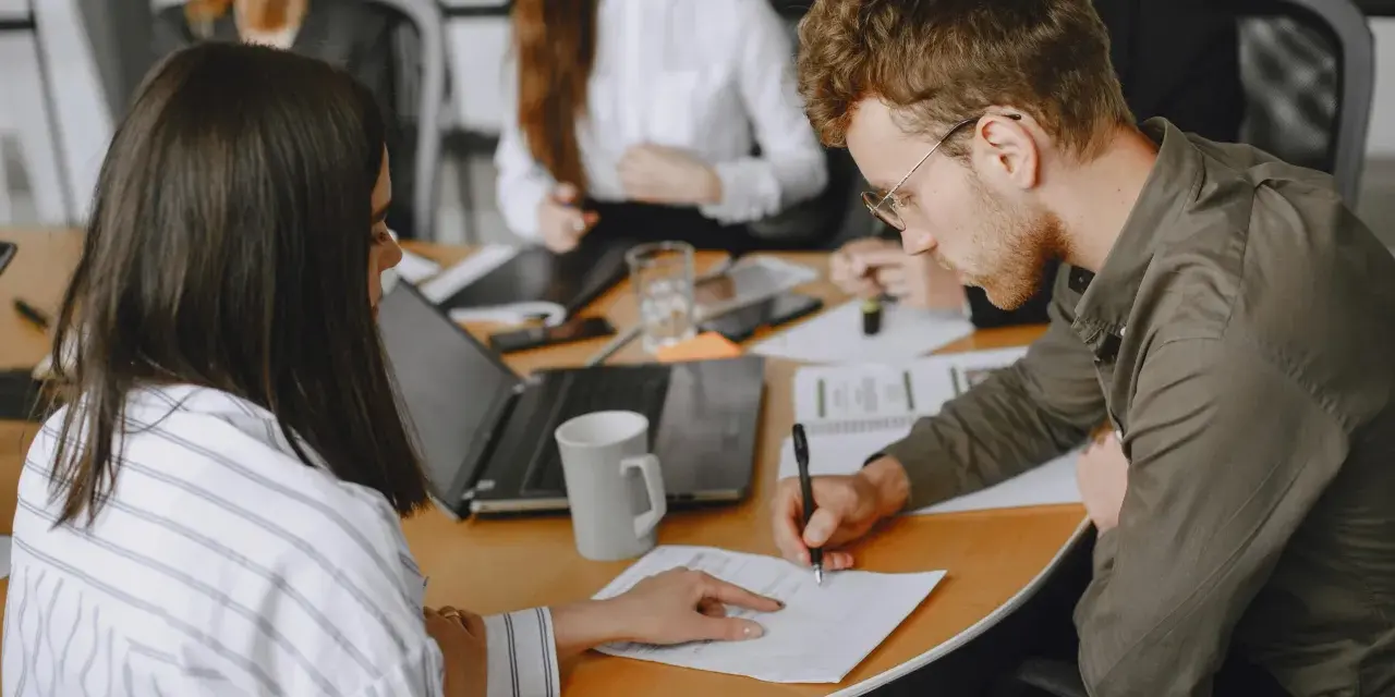 Uomini e donne in riunione, concentrati sul lavoro. Le 40 ore settimanali sono un impegno serio per raggiungere gli obiettivi.