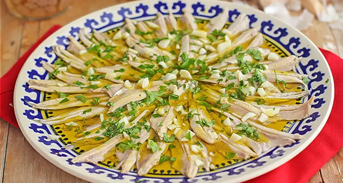 Boquerones en vinagre, un plato fresco y sabroso, servido en una fuente decorada con perejil y ajo picado.