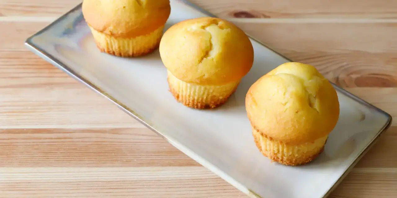 Tre soffici muffin allo yogurt dorati, pronti per essere gustati su un piatto rettangolare.
